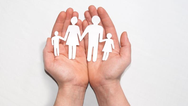 Hände die eine ausgeschnittene Familie aus Papier hält 