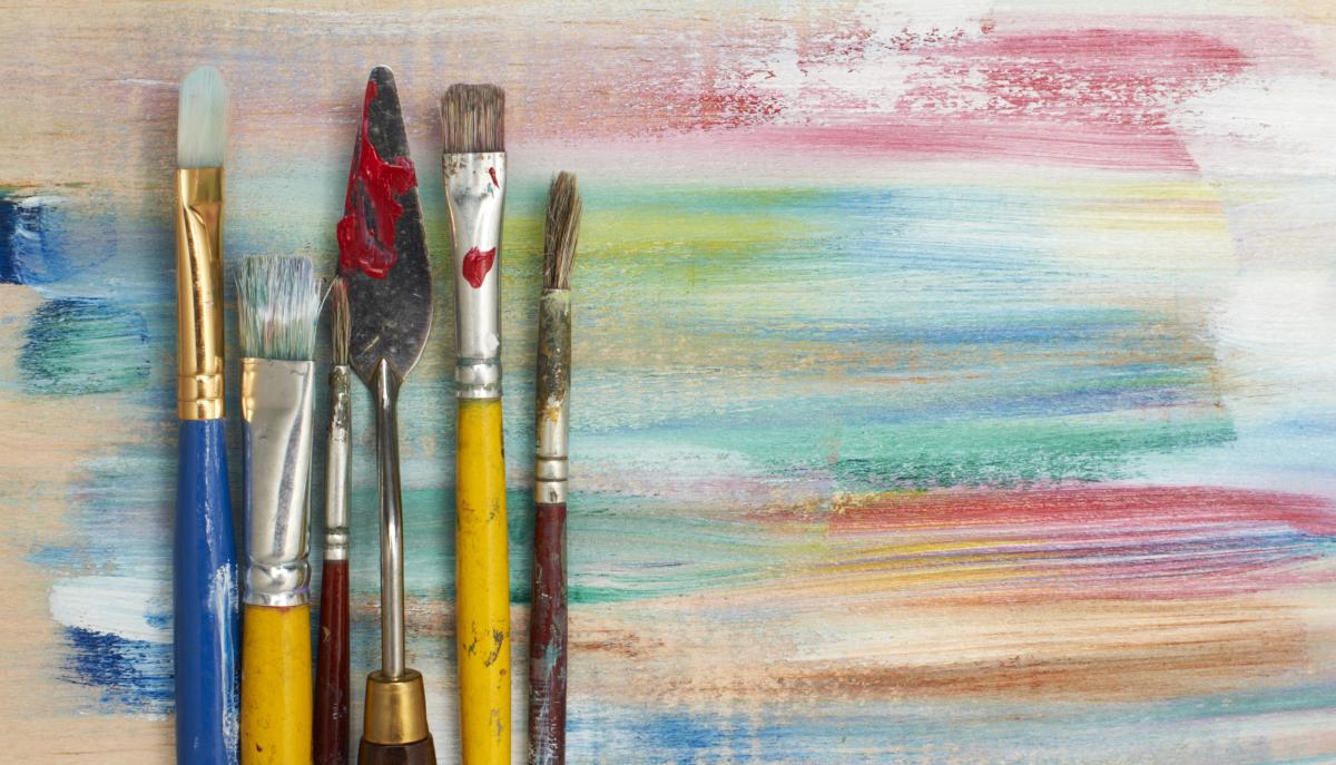 Pinsel und Spachtel vor farbiger Leinwand
