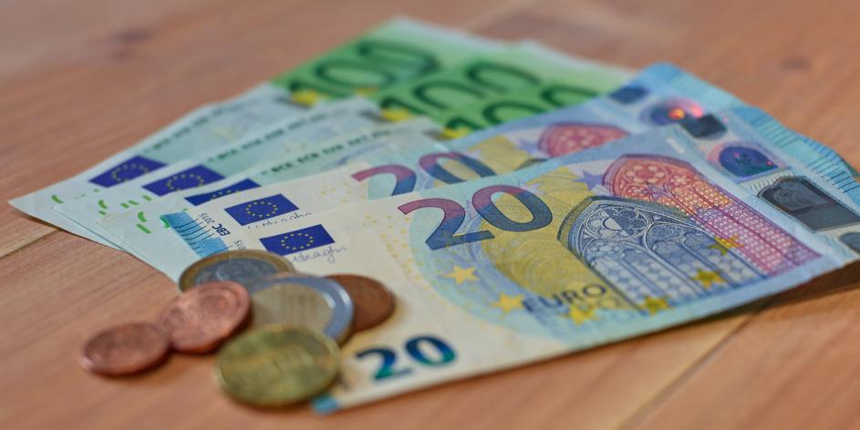 Aufgefächerte Geldnoten mit Münzgeld