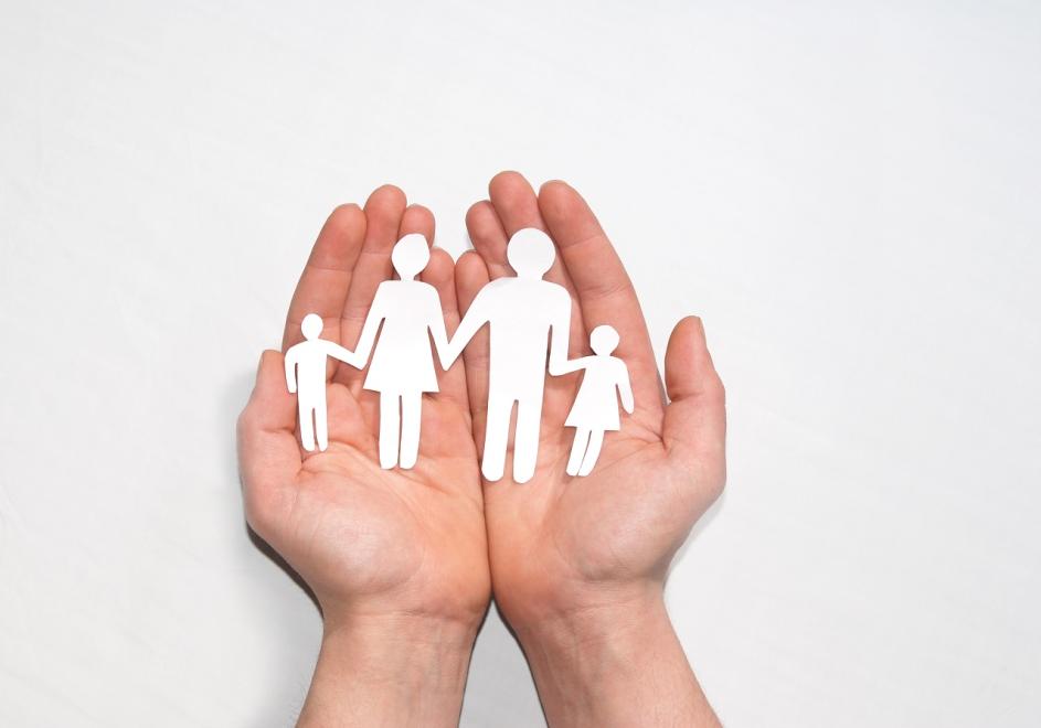 Hände die eine ausgeschnittene Familie aus Papier hält