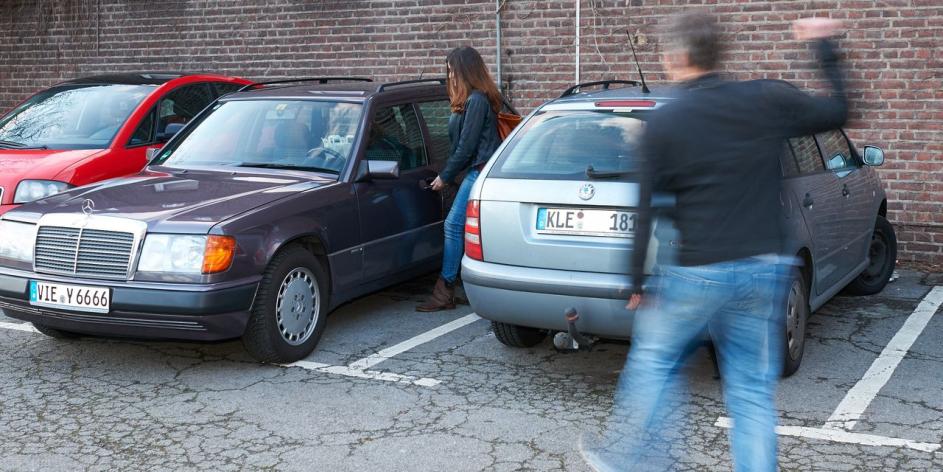 Eine Frau, die in ihr Auto steigen möchte und ein Mann der sie verfolgt