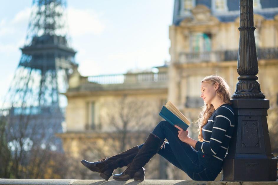 Frau liest ein Buch in der Nähe des Eifelturms in Paris