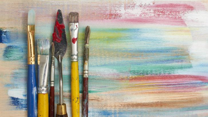 Pinsel und Spachtel vor farbiger Leinwand